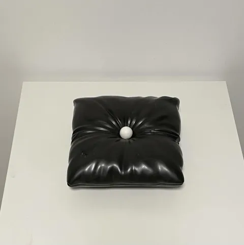 Black ceramic cushion with a single white ball pressed into its center.