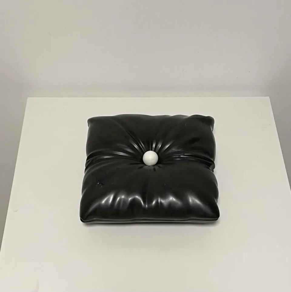 Black ceramic cushion with a single white ball pressed into its center.