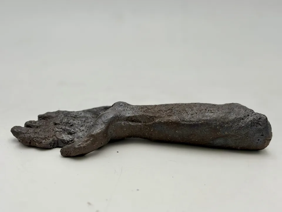 The hand from the side, fingers resting on the surface.