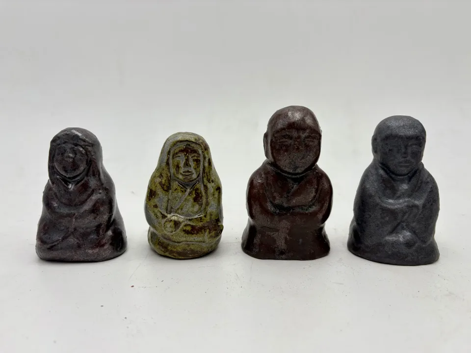 Four more: hooded figures in purple and pale green, a bald monk in brown, one in blue-grey.