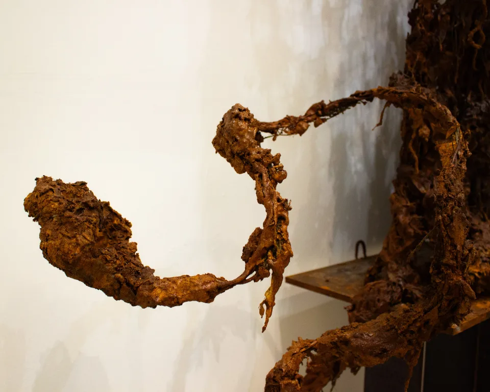 Detail: a rusted, crumbling limb reaching out sideways from the edge of a screen.