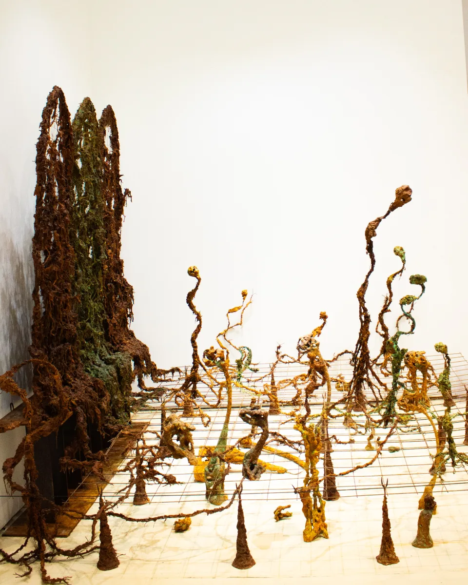 Installation view from the left: the screens at the edge, the field of sprouting figures spreading across the grid.
