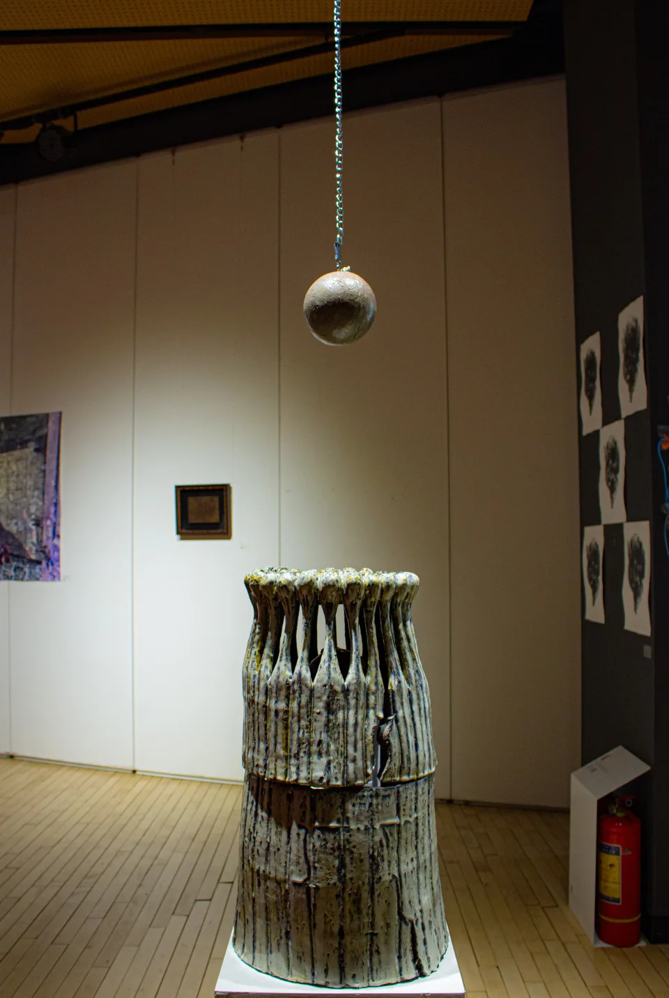 Installation view from the front: the vessel on its plinth, the sphere hanging above it.