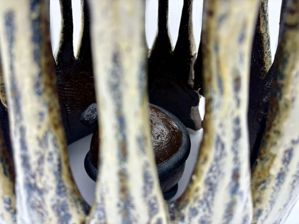 Detail: a dark sphere glimpsed between the vessel's slats.