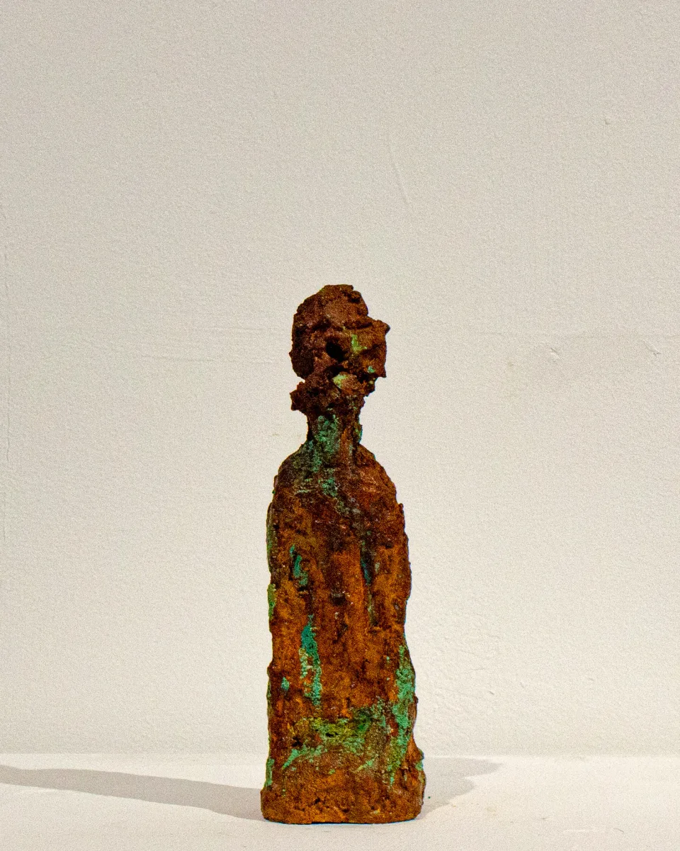 From the front: a small face on a robed, column-like body.