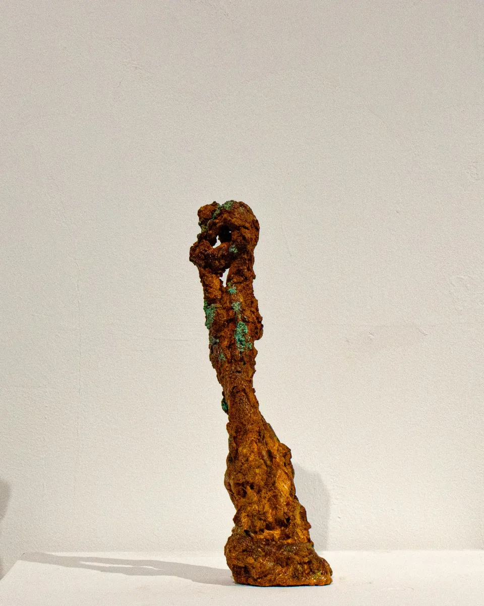 Small, twisting rust-coloured figure, its crumpled head turned upward.