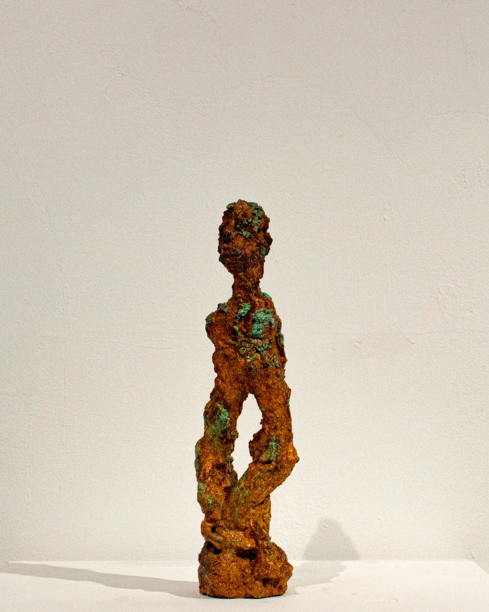 From the front: a standing body with a small face, flecked with green.