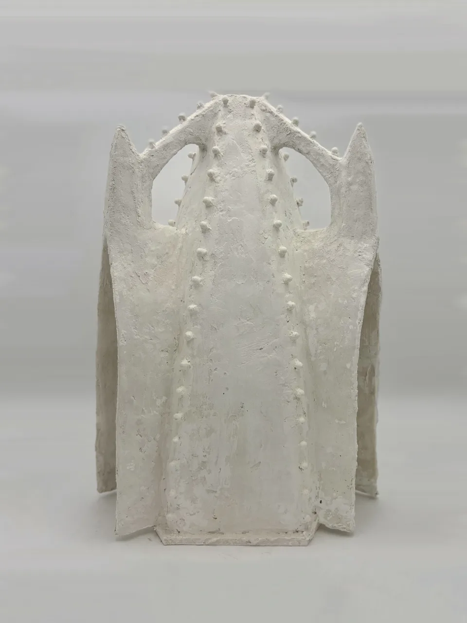 White plaster model of a tall, tent-like chapel with pointed gables, a narrow slit opening down the front and rows of small knobs along its ribs.
